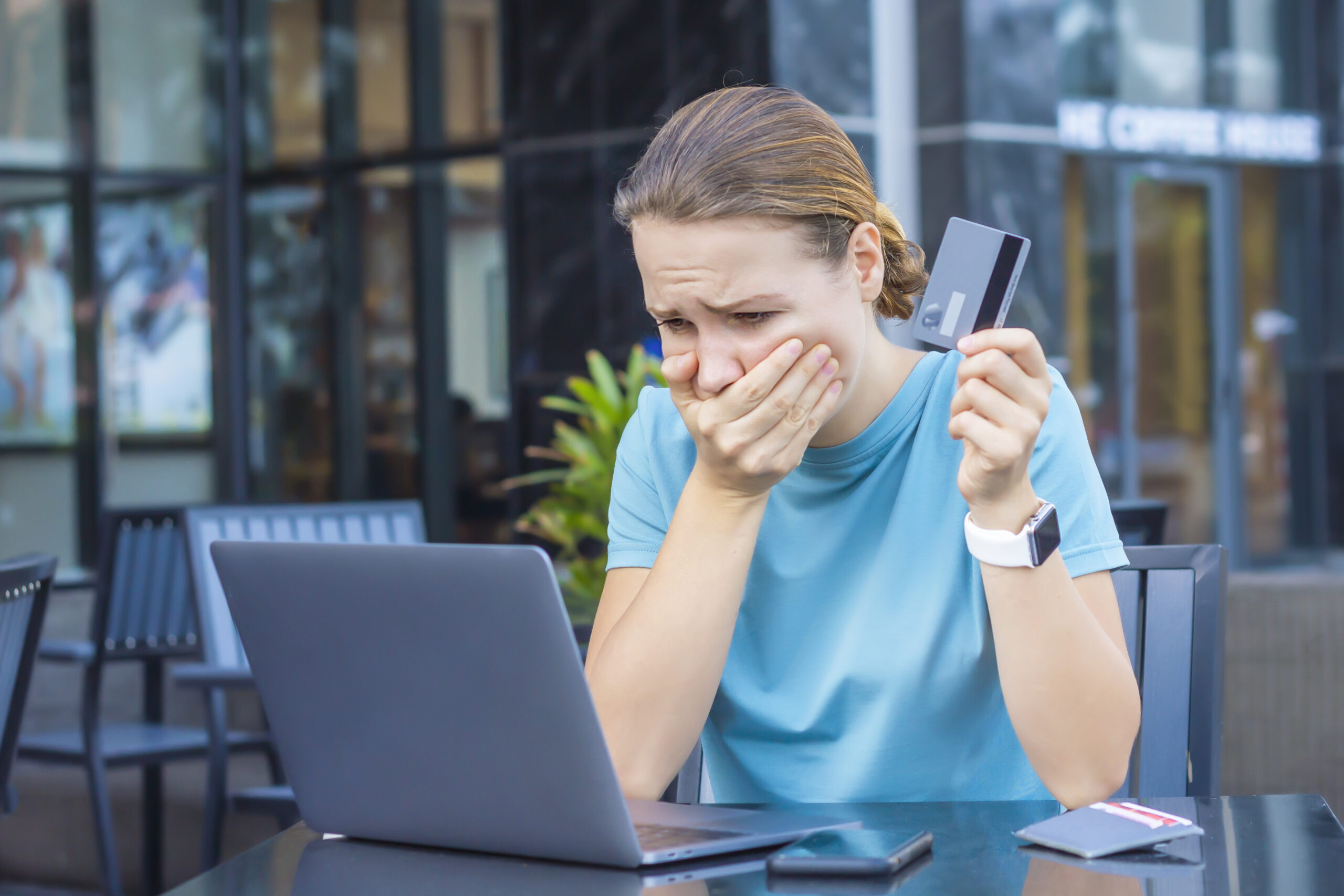 Femme devant son ordinateur et téléphone à la main, victime d'une fraude bancaire